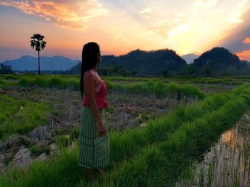 Side view of woman standing at farm during sunset