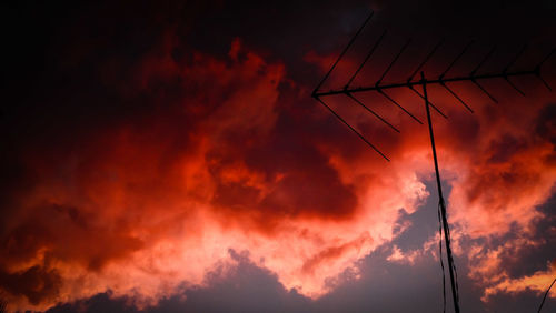 Low angle view of power lines against dramatic sky