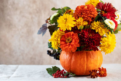 A beautiful autumn bouquet of yellow and red flowers in a pumpkin. the concept of autumn,