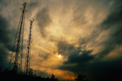 Low angle view of silhouette cranes against dramatic sky