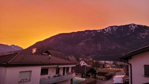 Houses by mountain against sky during sunset