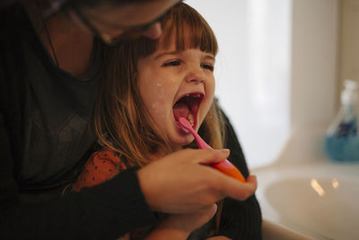 Mother brushing daughters teeth