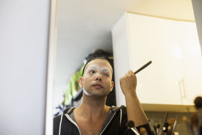 Young man applying drag makeup