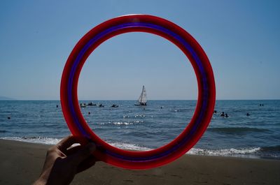 Cropped hand holding loop against sea