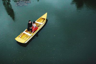 High angle view of people sitting on boat moored in lake