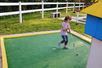 Full length of girl playing miniature golf at lawn