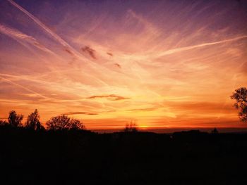 Silhouette trees against dramatic sky during sunset