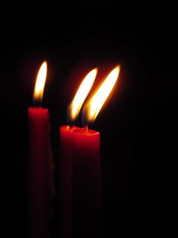 Close-up of candles burning in darkroom