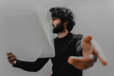 Man holding paper gesturing while standing against white background