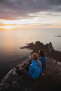 Rear view of couple looking at sea against sky during sunset