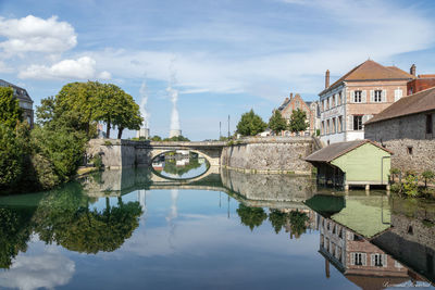 Arch bridge over river by building against sky