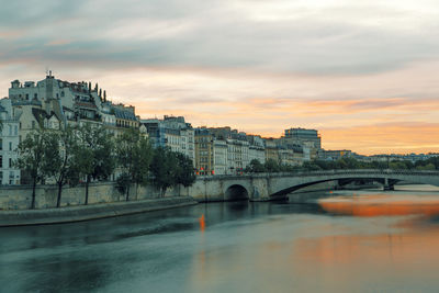 Bridge over river by buildings against sky in city