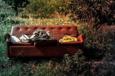 Abandoned sofa on field against trees