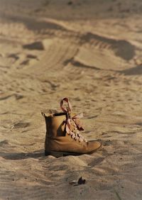 Close-up of girl's boots on sand at beach