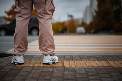 Low section of man standing on sidewalk in city