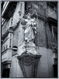 Low angle view of sculpture hanging against building