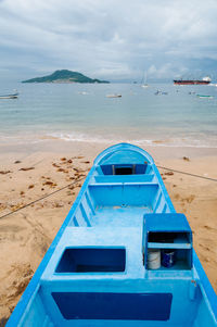 Boat moored at beach against sky