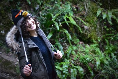 Portrait of smiling young woman standing against plants in forest