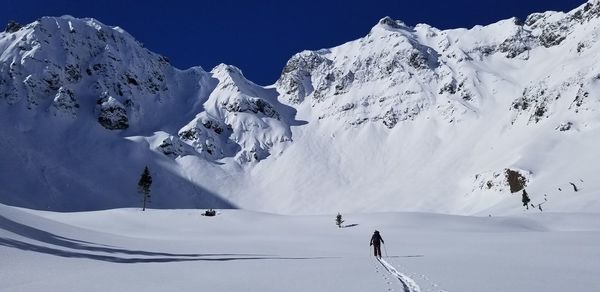 Person skiing on snow covered land by mountain against sky