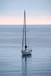 Sailboat sailing on sea against sky during sunset