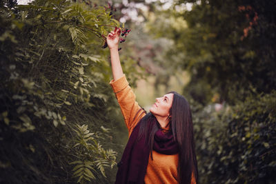 Full length of young woman standing against plants