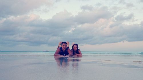 Portrait of smiling friends lying on shore at beach