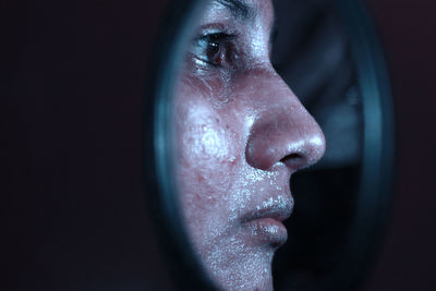 Close-up of thoughtful woman against black background