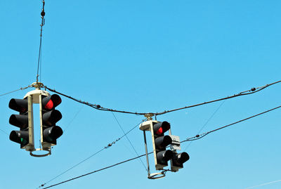 Low angle view of road signals against clear blue sky