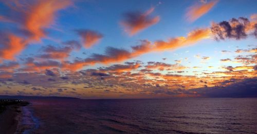 Scenic view of sea against dramatic sky during sunset