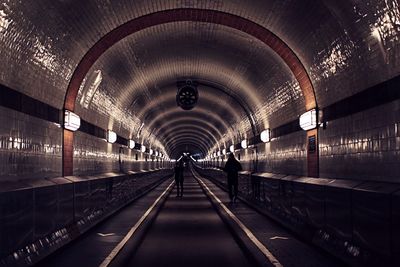 People walking in illuminated tunnel