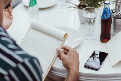 High angle view of man holding menu while sitting at table in restaurant