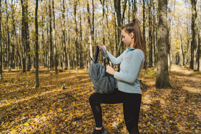 A girl in warm clothes walks through an autumn forest.