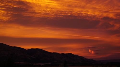 Scenic view of silhouette mountains against orange sky