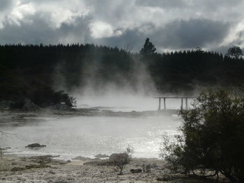 Walkway amidst geysers against sky