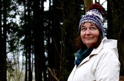 Portrait of smiling mid adult woman against trees