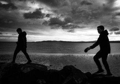 Full length of man standing on rock at beach against sky