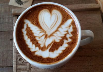 Directly above view of cappuccino with froth art served on wooden table
