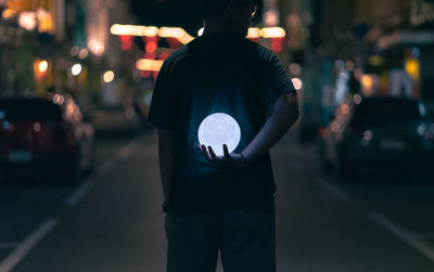 Rear view of man standing on street at night