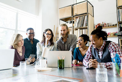 Happy business people working on laptop computer at conference table