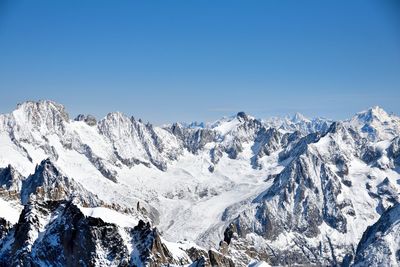 Scenic view of snowcapped mountains against clear blue sky