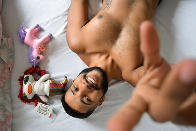 Portrait of shirtless young man lying on bed at home