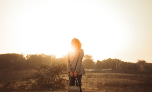 Low angle view of woman standing against sky during sunset