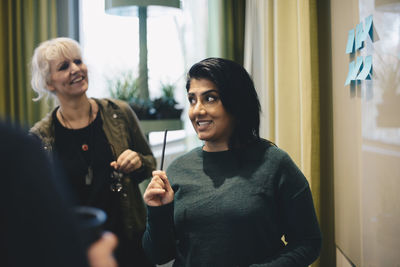 Confident businesswoman discussing with colleagues in board room