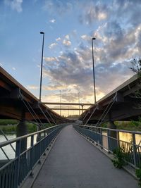 Bridge over road by buildings against sky