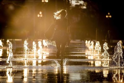 Rear view of woman running by fountain at street