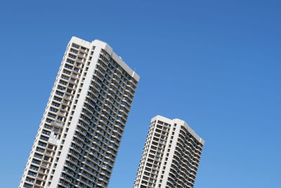 Low angle view of skyscrapers against clear blue sky