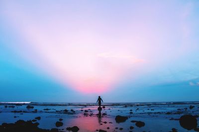 Silhouette people on beach against sky during sunset