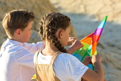 Brother and sister collect a kite in nature, close-up.