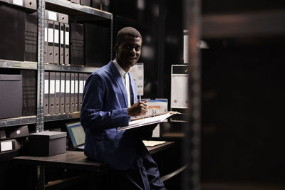 Side view of man using laptop while standing in workshop