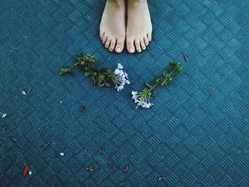 Low section of woman standing by flowers on metallic footpath